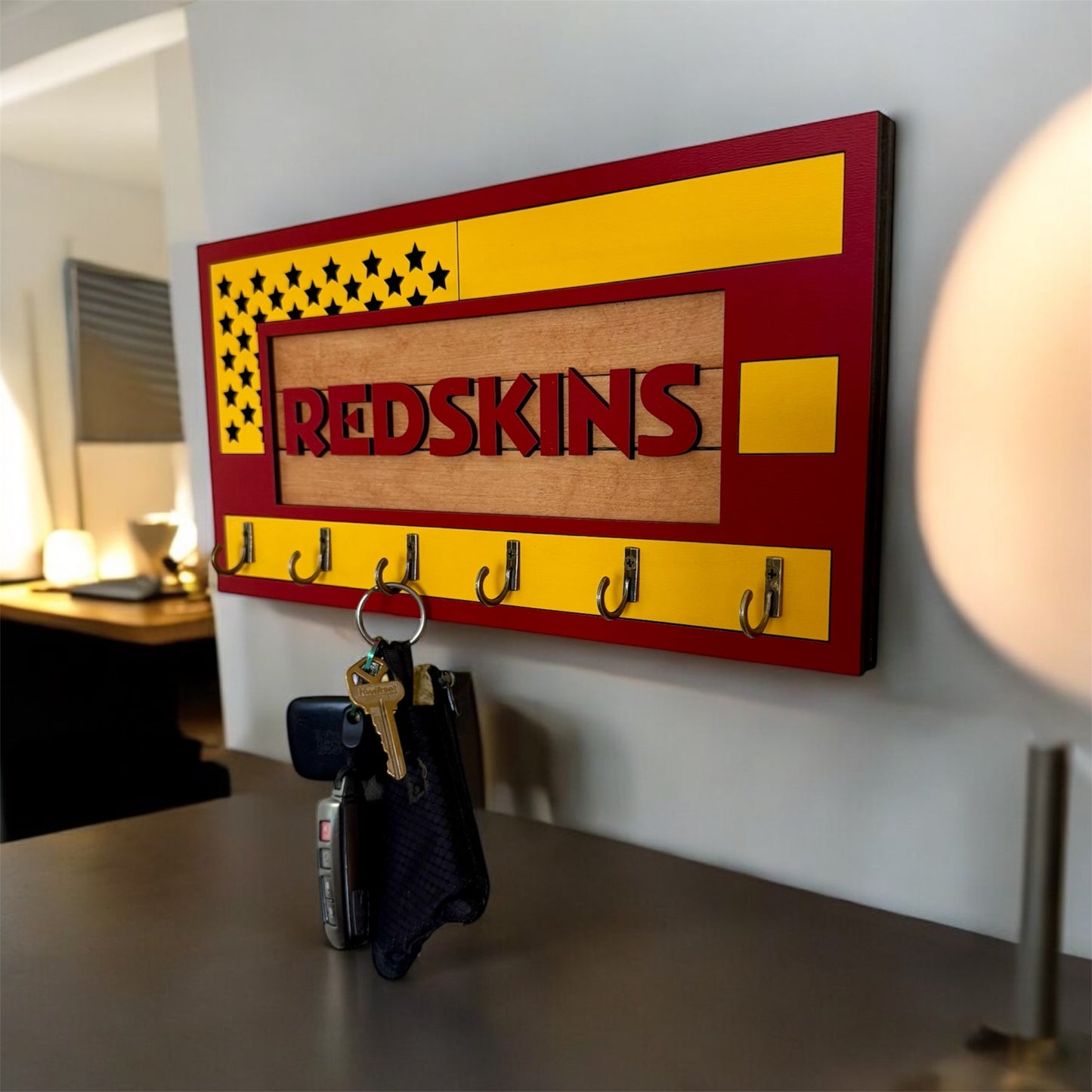 USA flag-inspired wooden key holder with “Redskins” in maroon letters, featuring yellow and maroon accents, six metal hooks, and a rustic maple wood background.