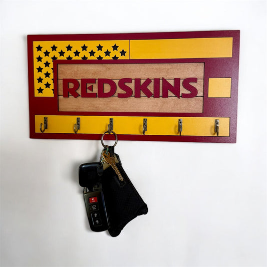 USA flag-inspired wooden key holder with “Redskins” in maroon letters, featuring yellow and maroon accents, six metal hooks, and a rustic maple wood background.