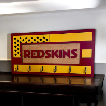USA flag-inspired wooden key holder with “Redskins” in maroon letters, featuring yellow and maroon accents, six metal hooks, and a rustic maple wood background.