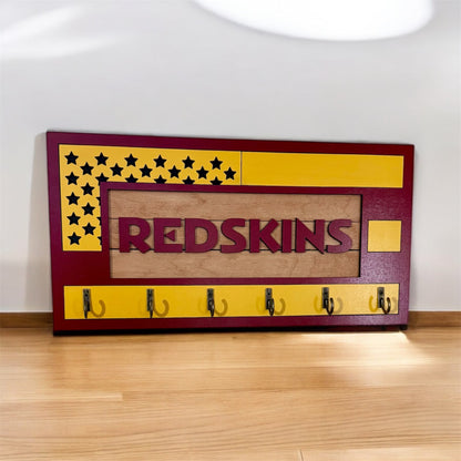USA flag-inspired wooden key holder with “Redskins” in maroon letters, featuring yellow and maroon accents, six metal hooks, and a rustic maple wood background.